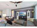 Comfortable living room with a large television, decorative cabinets, and a gray sectional sofa at 26049 W Matthew Dr, Buckeye, AZ 85396