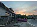New home under construction with a pink dumpster and scaffolding against a colorful sunset sky at 7141 E Ironwood Dr, Paradise Valley, AZ 85253