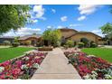 Inviting single-Gathering home with lush landscaping, including flowerbeds, and a welcoming walkway to the entrance at 8272 S Pecan Grove Cir, Tempe, AZ 85284