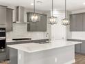 Modern kitchen features sleek gray cabinets, stainless steel appliances, a stylish range hood, and a central island at 17809 W Elm St, Goodyear, AZ 85395