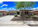 Inviting home exterior with stone detailing, a well-kept lawn, and a paved driveway, bathed in the warmth of a sunny day at 19245 W Pasadena Ave, Litchfield Park, AZ 85340