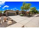 Beautiful home exterior with stone accents, a spacious driveway, and a well-manicured yard under a bright blue sky at 19245 W Pasadena Ave, Litchfield Park, AZ 85340