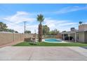 View of a backyard with a private pool, swing, brick fire pit, and artificial turf at 530 E Draper St, Mesa, AZ 85203