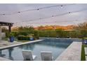 Sparkling pool with mountain views, lounge chairs and string lights at 8821 E Havasupai Dr, Scottsdale, AZ 85255