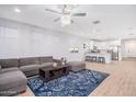 Open-concept living room with a gray sofa, blue rug, and modern lighting that connects to the kitchen at 17244 W West Wind Dr, Surprise, AZ 85387