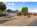 Wide driveway leads to a well-maintained home with green trees and landscape and exterior basketball hoop at 2616 E Des Moines St, Mesa, AZ 85213