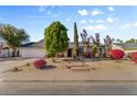 Inviting single-story home featuring a well-manicured front yard with mature trees and colorful flowering bushes at 2616 E Des Moines St, Mesa, AZ 85213