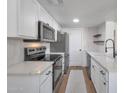 Open kitchen boasts stainless appliances, quartz counters, white cabinetry and wood look flooring at 948 S Alma School Rd # 13, Mesa, AZ 85210