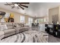 Open-concept living room with a plush sectional, ceiling fan and a view of the dining area at 18911 N Miller Way, Maricopa, AZ 85139