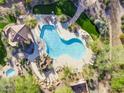 Aerial view of a sparkling blue swimming pool surrounded by lush landscaping and various seating areas and a hot tub at 7445 E Eagle Crest Dr # 1015, Mesa, AZ 85207