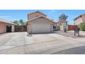 Wide shot of a beige two-story home, 2 car garage, neutral desert landscaping with secure gate at 13676 N 73Rd Dr, Peoria, AZ 85381