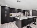 Stylish kitchen showcasing dark cabinets, quartz countertops, island with bar seating, and stainless appliances at 3008 W Michigan Ave, Phoenix, AZ 85053