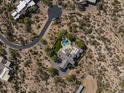 Overhead aerial view of a desert property with pool, green backyard, patio, rooftop deck, and circular driveway at 10160 E Whispering Wind Dr, Scottsdale, AZ 85255