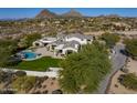 Breathtaking aerial view of the property featuring the pool, patio, green backyard, and views of the surrounding area at 10160 E Whispering Wind Dr, Scottsdale, AZ 85255