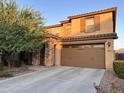 A tan two-story house featuring a stone column and a two-car garage door at 2665 E Gillcrest Rd, Gilbert, AZ 85298