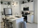 Bright kitchen featuring white cabinets, a stainless-steel refrigerator, an island, and modern light fixtures at 36354 W San Clemente Ave, Maricopa, AZ 85138