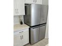The kitchen has a stainless-steel refrigerator, white cabinets and subway tile backsplash at 36354 W San Clemente Ave, Maricopa, AZ 85138
