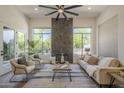 Bright living room featuring a fireplace, ceiling fan, and large windows at 7296 E San Alfredo Dr, Scottsdale, AZ 85258