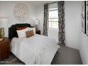 Well-lit bedroom showcases a bed with stylish pillows, decorative wall art, and large windows with patterned curtains at 8954 W Albeniz Pl, Tolleson, AZ 85353