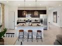 Bright kitchen with stainless steel appliances, dark cabinets, granite countertop, and stylish pendant lighting over a kitchen island at 8954 W Albeniz Pl, Tolleson, AZ 85353