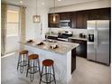 Modern kitchen features dark wood cabinets, stainless steel appliances, and a spacious island with bar seating at 8954 W Albeniz Pl, Tolleson, AZ 85353