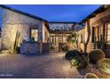 Desert home featuring a cozy courtyard with stone details and lush, well-lit desert landscaping at 10057 E Blue Sky Dr, Scottsdale, AZ 85262