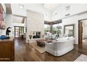 Bright living room with a stone fireplace, wooden floors, and large windows with outdoor views at 10057 E Blue Sky Dr, Scottsdale, AZ 85262