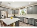 A modern kitchen featuring stainless steel appliances, gray cabinetry, and quartz countertops at 1635 N 208Th Ave, Buckeye, AZ 85396