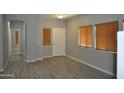 Open-concept living room featuring gray walls, faux-wood floors, and a neutral-toned front door at 17810 W Marshall Ln, Surprise, AZ 85388