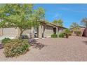 Front view of a charming single-story home with desert landscaping, manicured bushes, and a covered front porch at 18590 W Vogel Ave, Goodyear, AZ 85338