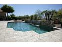 Beautiful in-ground pool featuring multiple waterfalls and travertine tile decking at 27083 W Marco Polo Rd, Buckeye, AZ 85396