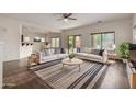Bright living room with modern sofas, a stylish rug, and a ceiling fan at 41227 W Granada Dr, Maricopa, AZ 85138
