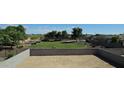 Large, fenced-in backyard with grass and trees beyond the block fence, perfect for outdoor activities and relaxation at 19117 W Missouri Ave, Litchfield Park, AZ 85340