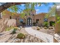 Stunning custom home with a stone tower, barrel tile roof, landscaped yard, and welcoming walkway to the arched entry door at 37334 N Winding Wash Trl, Carefree, AZ 85377
