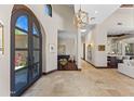 Light-filled foyer with travertine flooring, grand piano, designer lighting, and arched doorway provides a welcoming entrance at 37334 N Winding Wash Trl, Carefree, AZ 85377