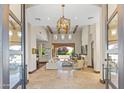 Spacious living room with travertine floors, wood beams, large windows, statement light fixture, and retractable glass doors at 37334 N Winding Wash Trl, Carefree, AZ 85377