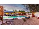 Beautiful backyard with a sparkling pool, rock features, and charming outdoor furniture under festive string lights at 5253 E Waltann Ln, Scottsdale, AZ 85254