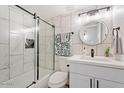 Modern bathroom with marble-style tile, a glass enclosed shower, and a sleek vanity with a round mirror at 623 W Guadalupe Rd # 288, Mesa, AZ 85210