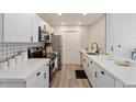 Modern kitchen features white cabinets, quartz countertops, stainless steel appliances, and decorative backsplash at 623 W Guadalupe Rd # 288, Mesa, AZ 85210