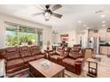 Spacious living room with leather sofas, a ceiling fan and a large window with backyard views at 17139 S 174Th Dr, Goodyear, AZ 85338
