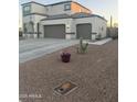 This home boasts a spacious driveway, three-car garage, landscaped front yard with decorative cactus, and stucco siding at 3012 N 310Th Ln, Buckeye, AZ 85396
