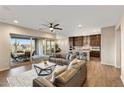 Bright and airy living room with a ceiling fan, large windows, and seamless access to the gourmet kitchen at 32237 N 133Rd Dr, Peoria, AZ 85383