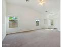 Bright and airy living room featuring neutral carpet, two windows, and a vaulted ceiling with a ceiling fan at 89 S 151St Ave, Goodyear, AZ 85338