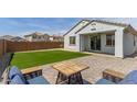 Landscaped backyard featuring lush artificial grass, a paver patio, and outdoor seating area at 14269 W El Cortez Pl, Surprise, AZ 85387