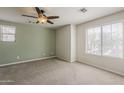 Bright bedroom with neutral carpet, a ceiling fan, and ample natural light from a large window at 2144 W Barwick Dr, Phoenix, AZ 85085