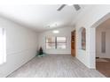 Spacious room with laminate flooring, neutral paint, a ceiling fan, and an arched entry and built-in bookcase at 3206 W Knudsen Dr, Phoenix, AZ 85027
