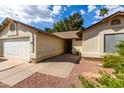Single-Gathering home with neutral tones, desert landscaping, and an attached two-car garage at 4102 W Fallen Leaf Ln, Glendale, AZ 85310