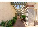 Picturesque walkway with brick pavers, lush greenery, and a charming trellis overhead at 9012 S 47Th Pl, Phoenix, AZ 85044