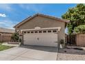 Tan single-story home showcasing a two-car garage, low maintenance landscaping, and ample driveway space at 9463 W Ross Ave, Peoria, AZ 85382