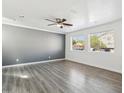 Bright living room with gray accent wall, hardwood floors, ceiling fan, and natural light from two windows at 1466 E Avenida Fresca --, Casa Grande, AZ 85122